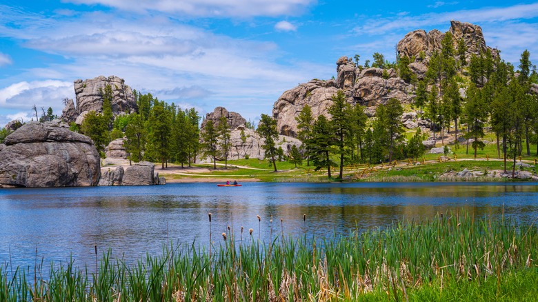 Sylvan lake surrounded by grass, trees, and rock formations in Custer State Park