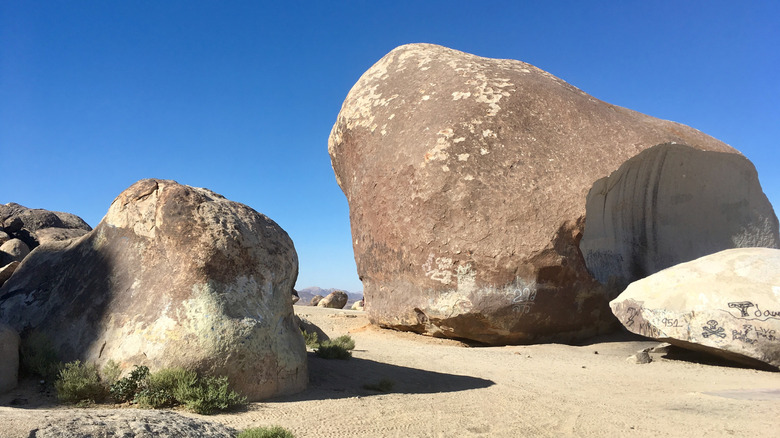 A wedge of the Giant Rock that split away can be seen next to the boulder, covered in graffiti