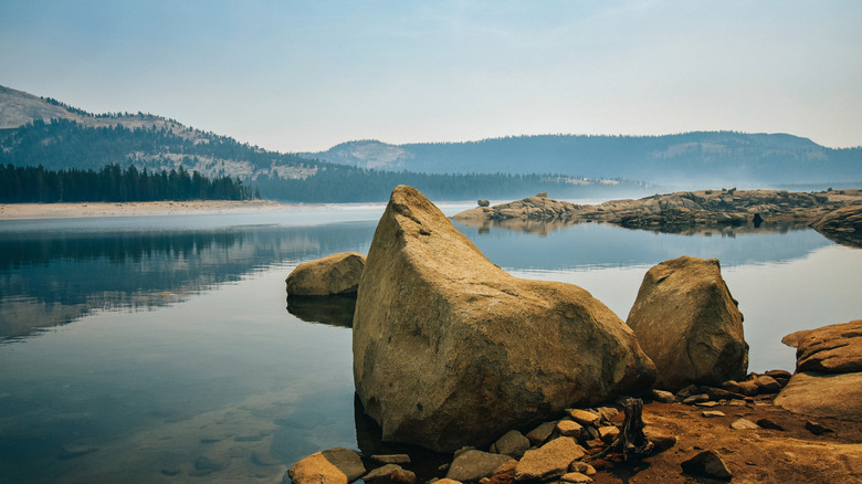 A view of Courtright Reservoir with a boulder in the foreground and mountains in the background