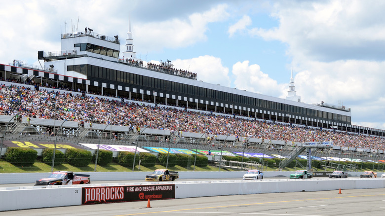 View of the Poconos Raceway with crowd in the stands and race trucks driving on track.