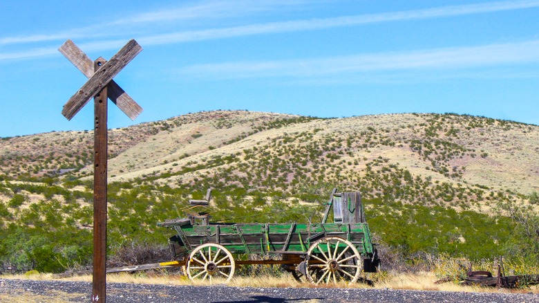 Wooden post and old carriage in front of hill in Shakespeare, New Mexico