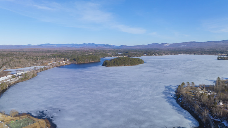 Ariel view of Island Pond at Brighton State Park, Vermont, during wintertime, with ice covering the surface and hills in the distance