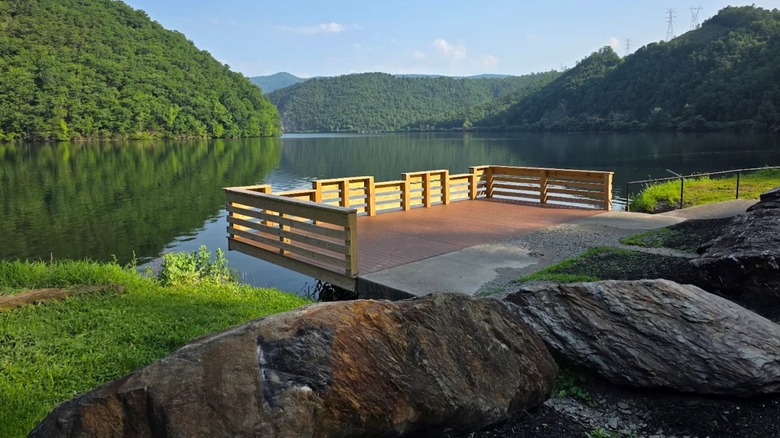 Views of a wooden pier, overlooking a pond, with lush rolling hills in the background, at Smoky Mountain National Park.