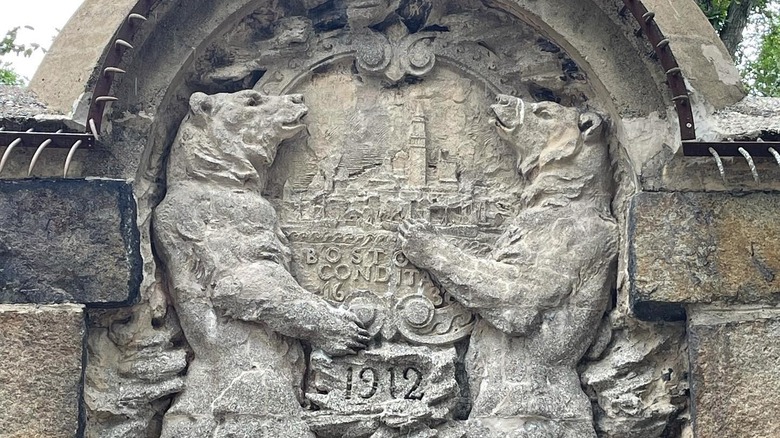 Stone relief of two bears holding up a seal at the old bear dens in Franklin Park, Boston