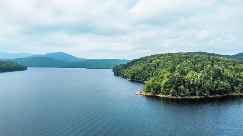 Harriman Reservoir in Vermont during an overcast day with trees, mountains, and shoreline in the background.