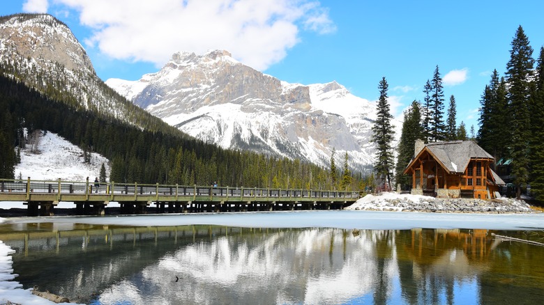 blue sky over a wooden building and lake and snowy mountains