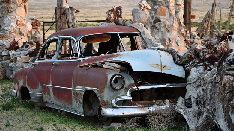 Abandoned vintage car merged with rocks and trees in Thunder Mountain Monument Nevada