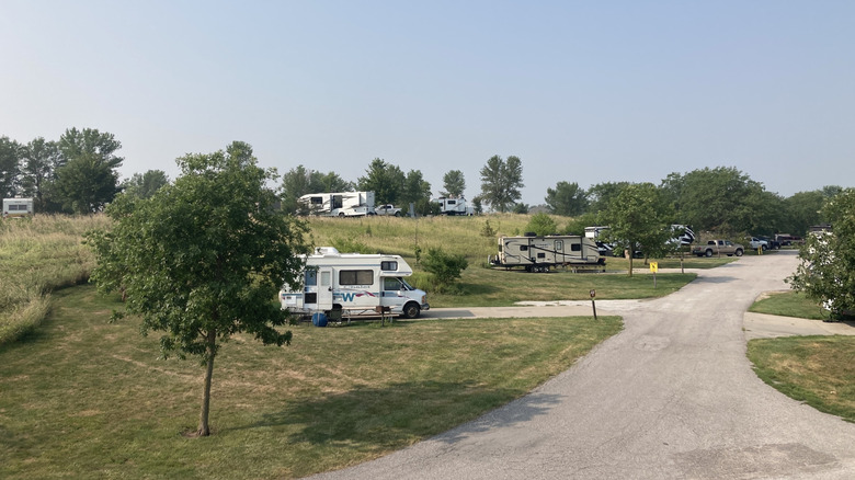 RVs backed into paved campsites on the left with a paved road curving off to the right at Walnut Creek Campground