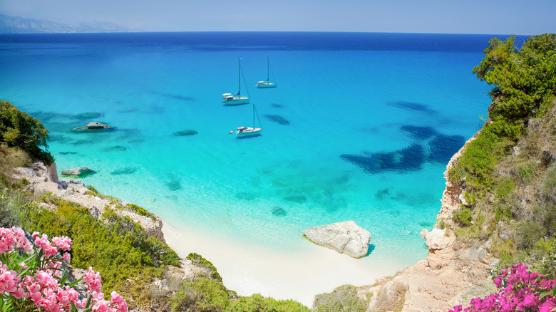 boats floating in turquoise water off a beach in sardinia