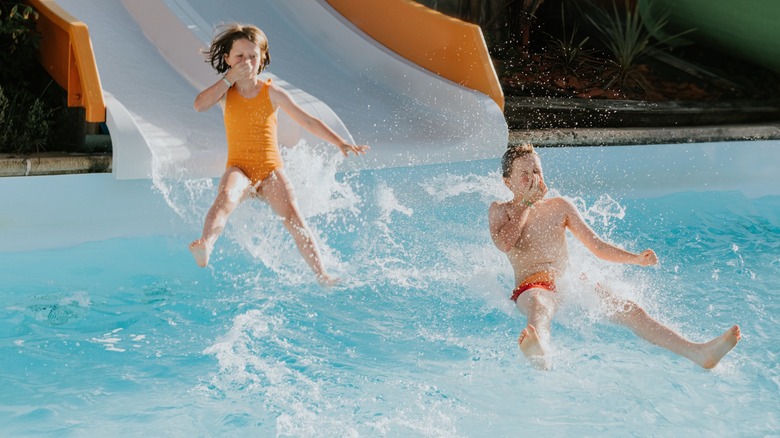 Two kids falling into a pool at the end of a waterslide