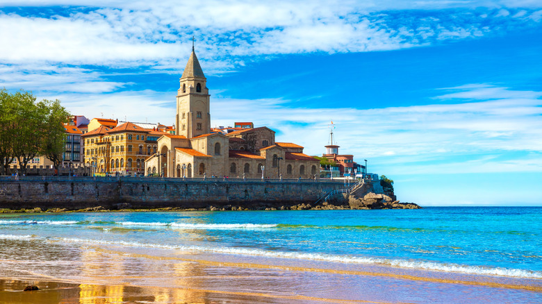 the view of a church above the sea from Playa de San Lorenzo in Gijon