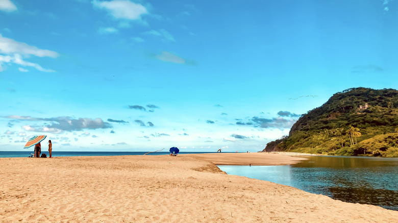 Golden sand with a jungle covered hill in the distance on Lo de Marcos beach