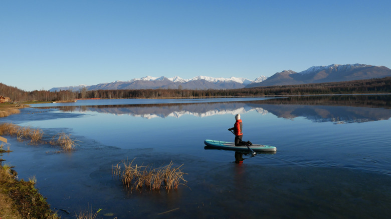 A woman paddleboarding on a lake in Alaska