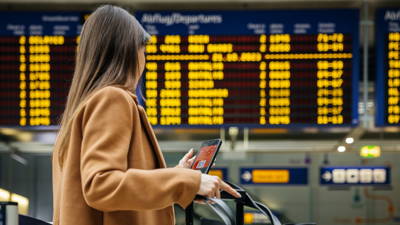Passenger checking phone near departure board
