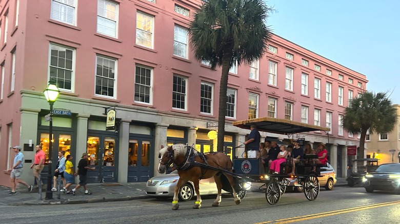 A horse-drawn carriage drives past colorful buildings on East Bay Street near High Cotton restaurant in Charleston, South Carolina