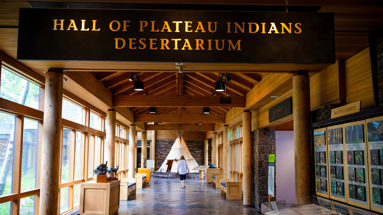 Hall of Plateau Indians Desertarium sign above woman walking towards tipi