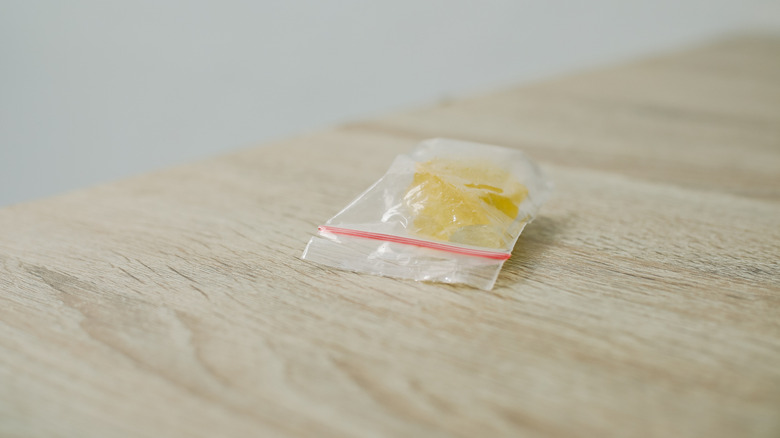 Close-up of crystal meth in a plastic bag on a light-colored wood table, representing the dangers of drug abuse and addiction