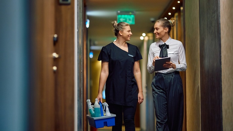 A hotel manager and housekeeping staff in a hotel corridor