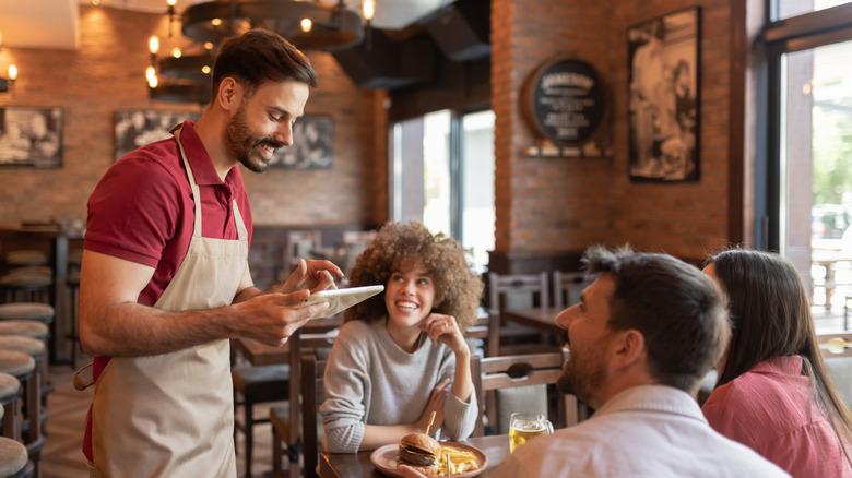 Diners speaking with a waiter at a restaurant