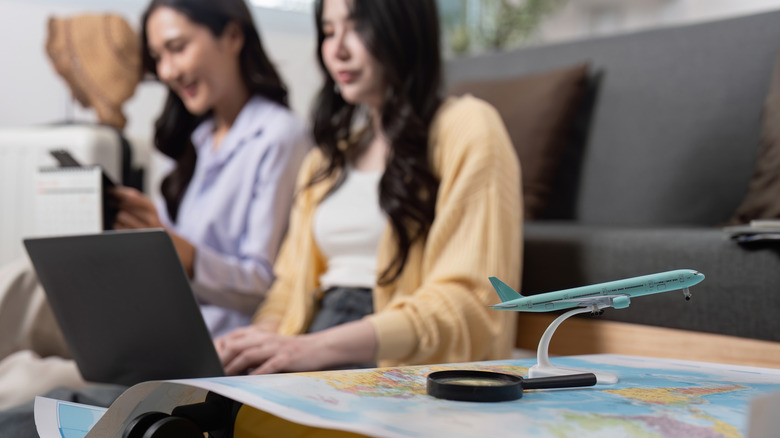 Friends researching destinations with laptop and map