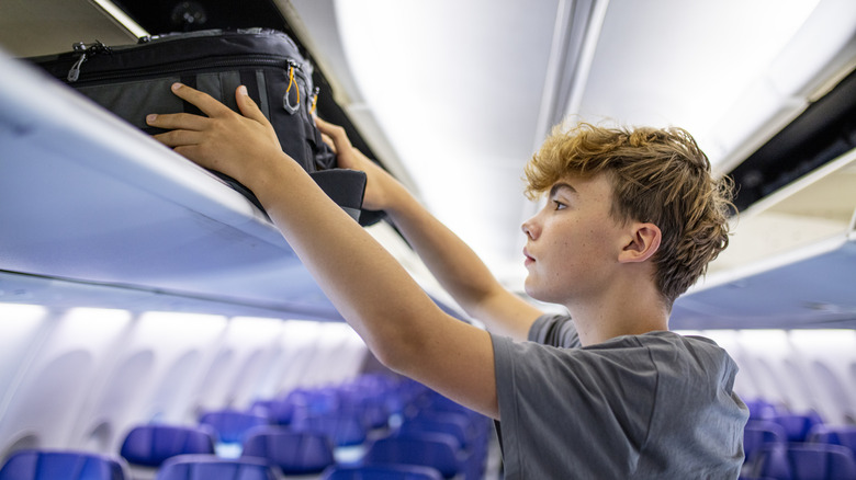 Teenage boy with suitcase on plane