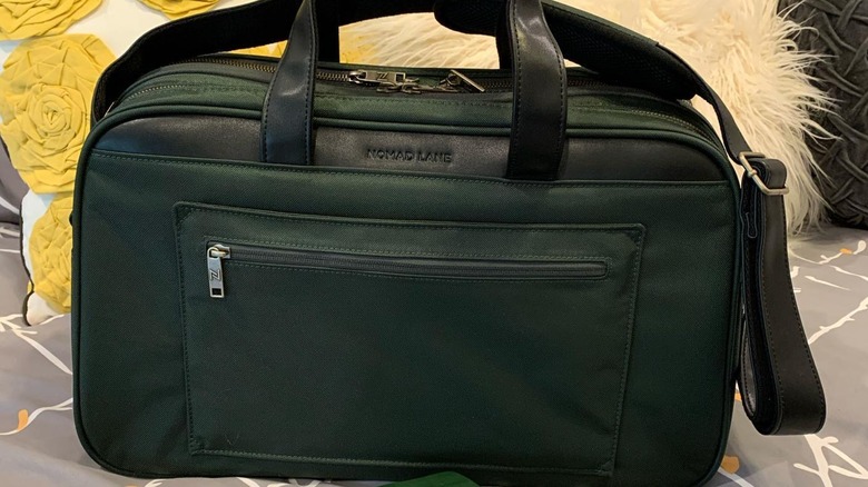 Green Nomad Lane Bento Bag sitting on a bed