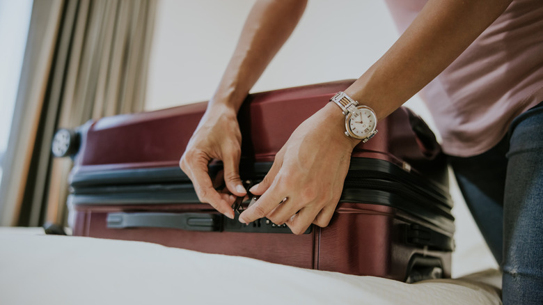 Someone locking their suitcase in a hotel room