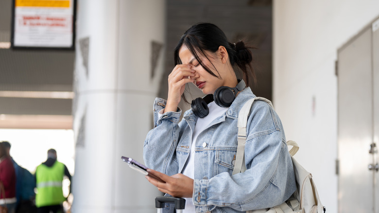 A frustrated traveler at the airport checks her phone