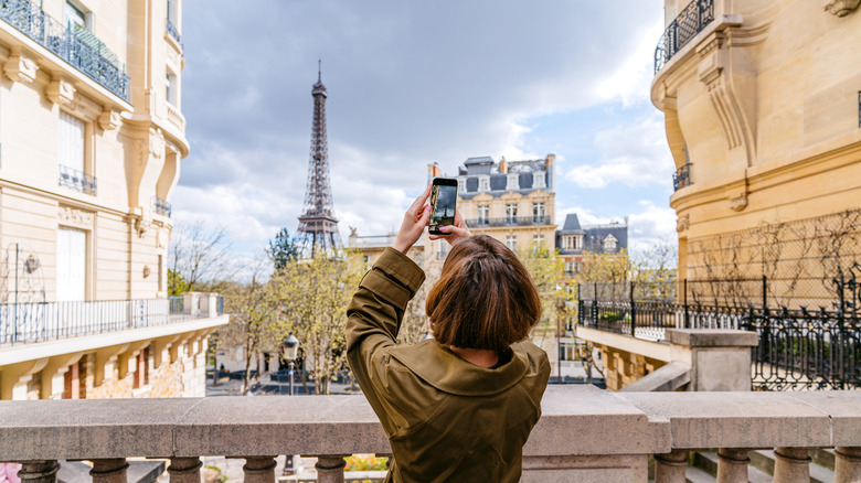 A tourist taking a photo of the Eiffel Tower