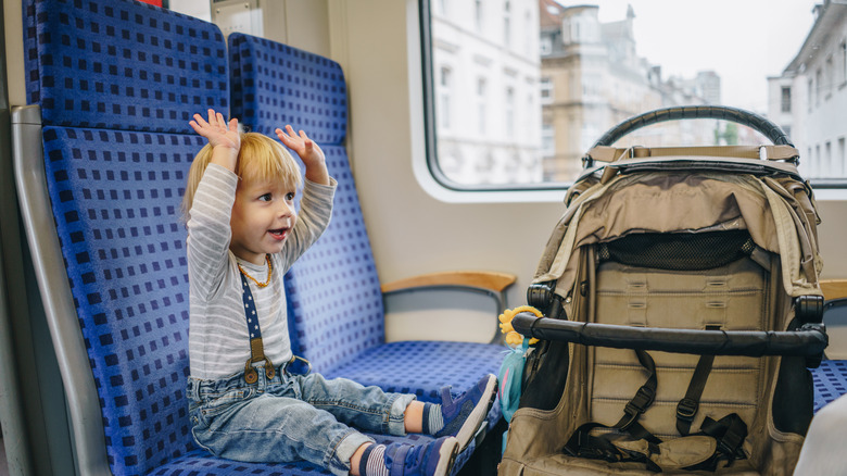 Happy little boy sits on a train overlooking a European city