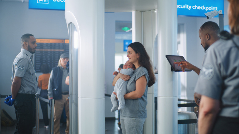 A baby held by a woman going through TSA airport security