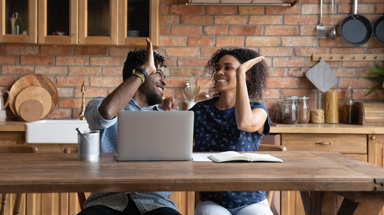 Couple high five with computer