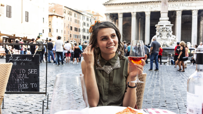 Young woman eating pizza and wine in an Italian piazza
