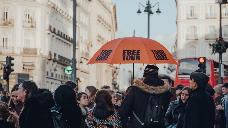 Madrid, Spain - January 26, 2020: Group of tourists gathered on Puerta del Sol, a public square in Madrid and one of the best known and busiest places in the city, for a free guided tour.