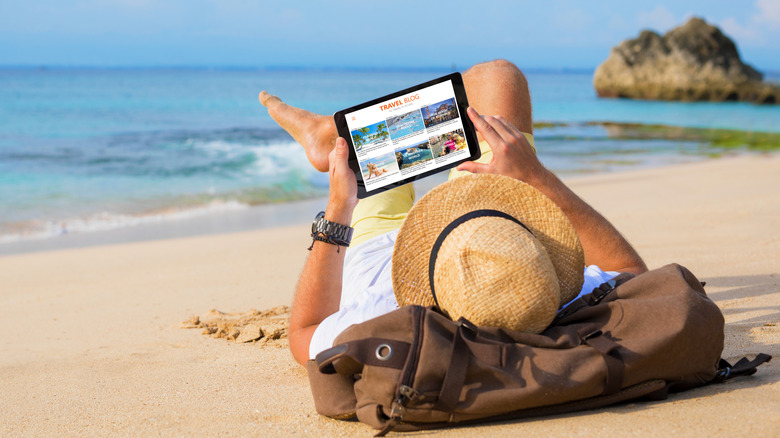 A traveler reading a travel blog on the beach