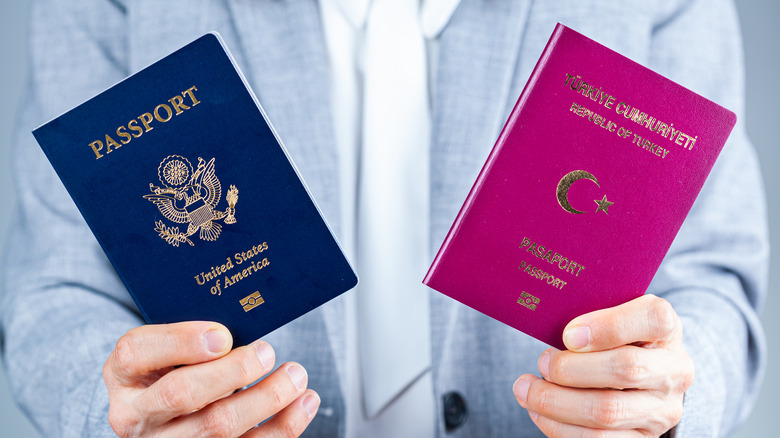 A person holding both a US passport and a Turkish passport in both hands