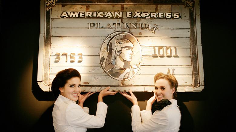 Women pointing to American Express Platinum sign