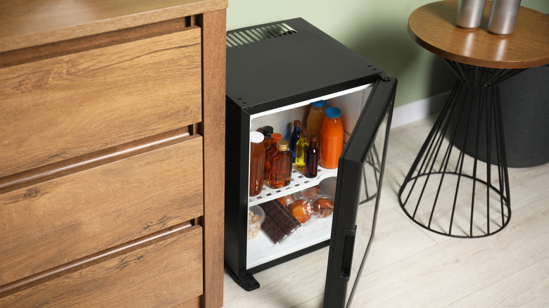 An open hotel minibar fridge showing various bottles of drinks and snacks