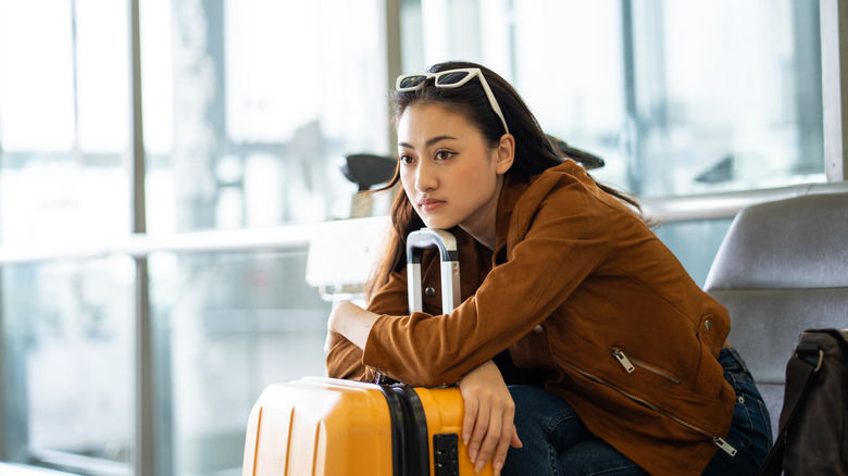 Unhappy woman waits with her suitcase at an airport