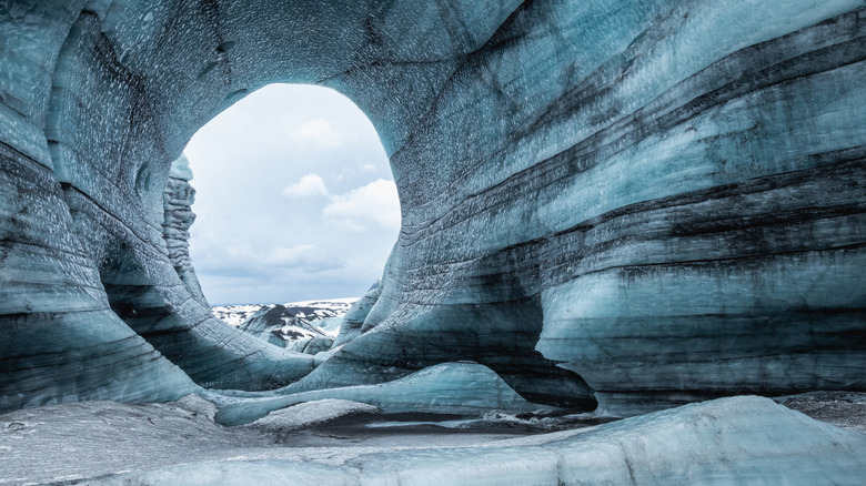 White, grey, and black layered walls of ice and volcanic ash in the Katla Ice Cave in Iceland