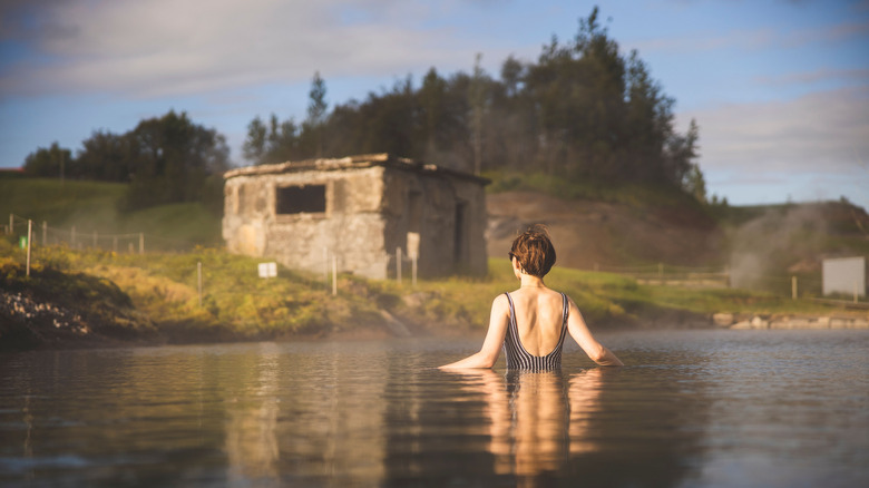 A woman swims in the Secret Lagoon, a geothermal area near Flúðir in Iceland, at sunset