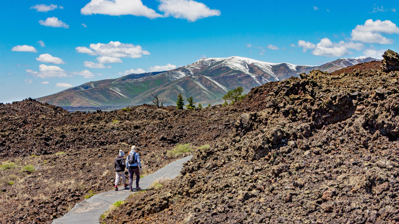 Hikers walk on a trail in the Craters of the Moon National Monument and Preserve