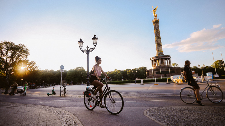 Woman cycling with the Berlin Victory column in the background.