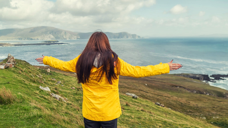 Back view of a girl in a yellow jacket facing the waters of Achill Island in Ireland