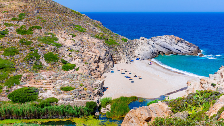 A sandy beach between cliffsides dotted with lush greenery