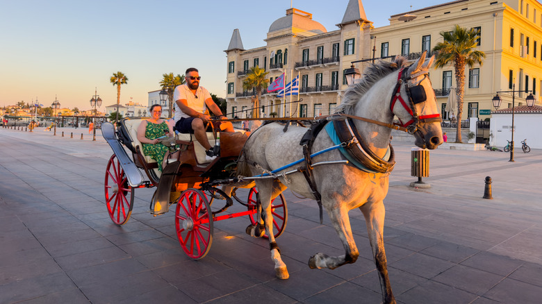 A horse-drawn carriage carrying a tourist along a boardwalk at sunset.
