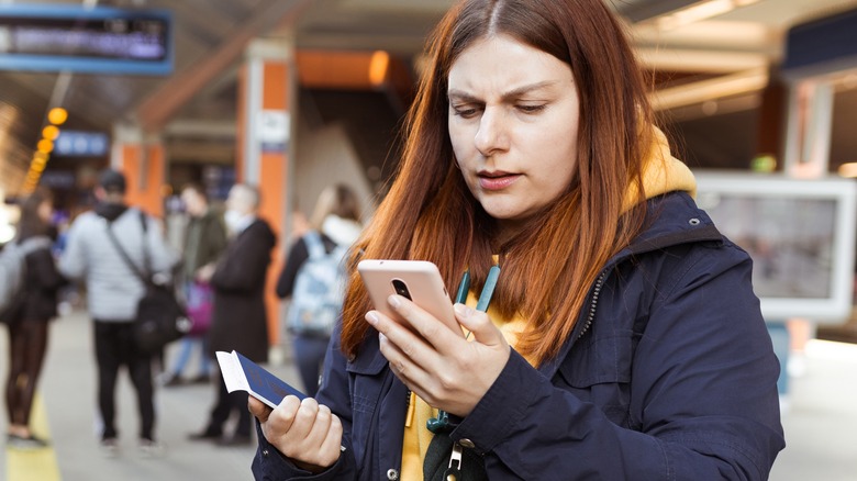 sed woman holding passport looking at phone