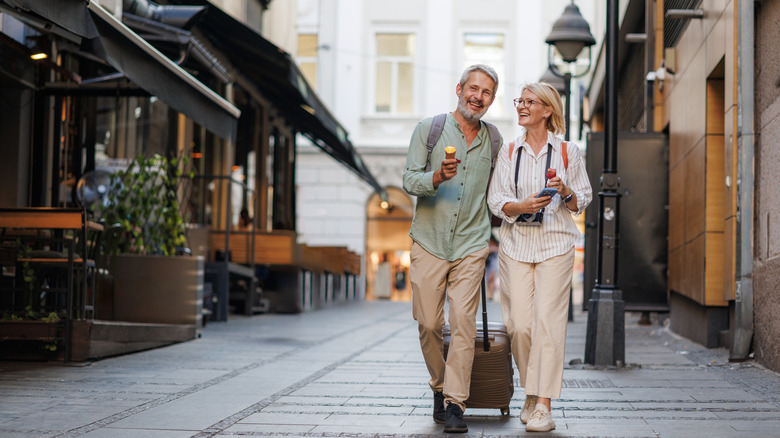 A couple sightseeing with a rolling suitcase