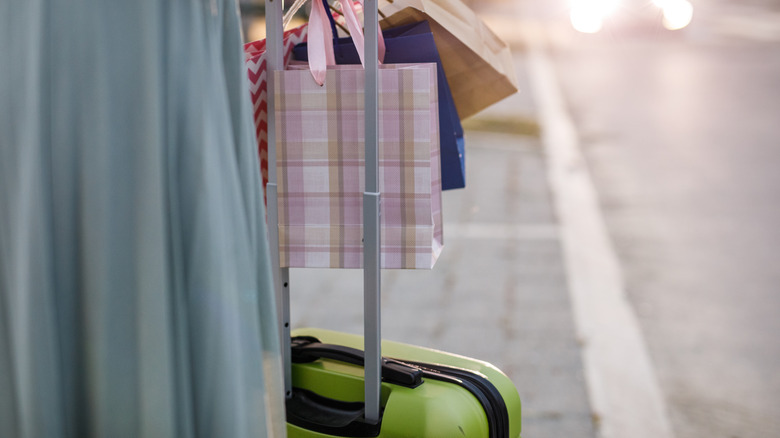 Person pulling suitcase and holding gift bags