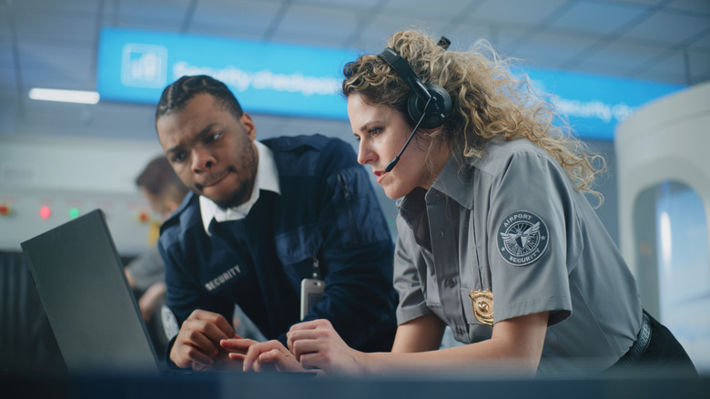 Two TSA agents checking something suspicious on a screen